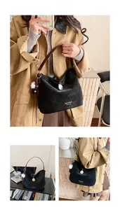 Detail view of black matte hobo bag with brown leather strap and decorative charms