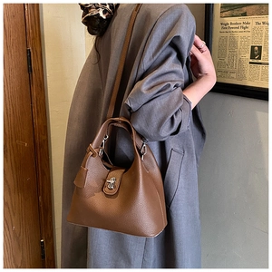 Detail of brown lychee grain leather bucket bag featuring a silver twist lock closure
