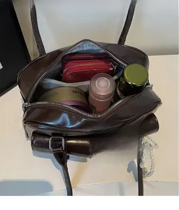 Macro shot of brown faux leather shoulder bag showing spacious interior and pocket
