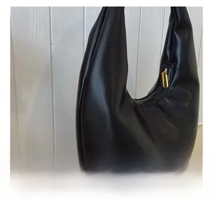 Detail view of the black leather hobo bag showing soft texture and gold metal zipper