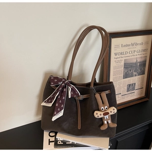 Detail of dark brown suede tote bag with a silk scarf and cute rabbit charm decoration