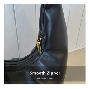 Close-up of the smooth gold metal zipper on a black leather half-moon bucket bag