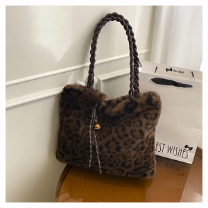 Detail of leopard print plush tote bag with woven leather handles and pompom charm