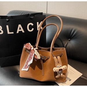 Detail of brown suede tote bag with leather straps, printed scarf and rabbit charm