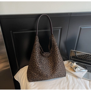 Détail du sac cabas léopard avec bandoulière marron sur une literie blanche
