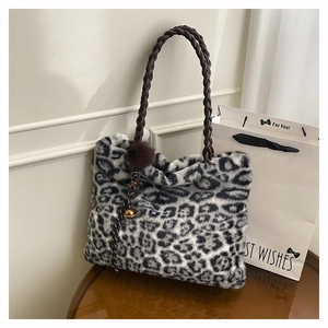 Detailed close-up of leopard print faux fur tote with woven handles and pompom charm
