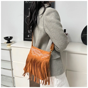 Detail of vintage brown suede crossbody bag with elegant white embroidery and long tassels
