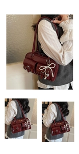 Detail of burgundy leather shoulder bag with buckle pockets and pearl bow charm accessory