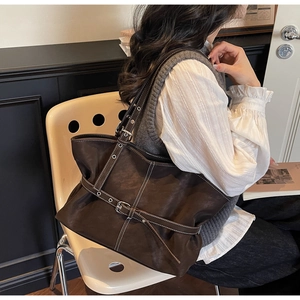 Vue détaillée du sac cabas marron foncé avec boucles argentées et coutures blanches contrastées