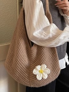 Brown knit tote bag with daisy flowers shown from a side view on a female model