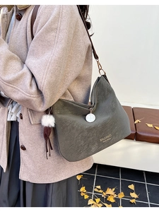 Detail view of olive green retro tote bag featuring wide strap and decorative tassel charm