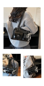 Detail view of black patent leather shoulder bag with pockets and pearl bow charm