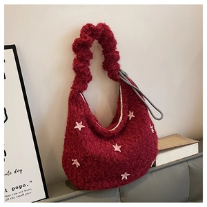 Detail of red plush shoulder bag featuring pink star motifs and a stylish ruffled handle