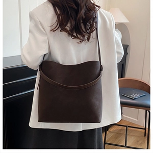 Dettaglio della tracolla larga e della trama marrone scuro opaca su una borsa tote vintage