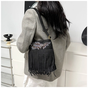 Detail of bohemian black suede shoulder bag with colorful embroidery and long tassels