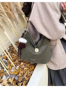 Close-up of dark green hobo bag featuring litchi texture and cute plush glove charm