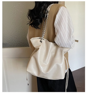 Detail of off-white large leather tote bag with silver chain strap shown on model's back
