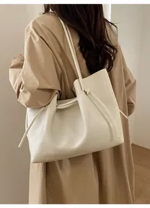 Close-up of beige leather tote bag with knotted drawstring handle detail and pebble texture