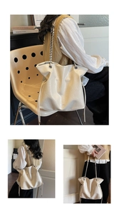 Detail of off-white faux leather tote bag with metal chain strap and drawstring closure