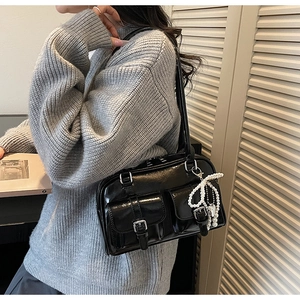 Close-up of black patent leather underarm bag featuring double pockets and pearl charms