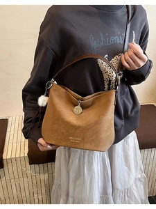 Detail of vintage brown suede tote bag with gold coin charm and plush ball accessory
