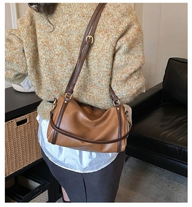 Close-up of brown patchwork leather bag with golden buckles and shoulder strap detail