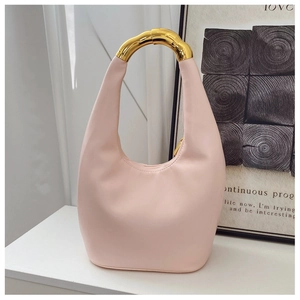 Detail of light pink hobo bag featuring a polished gold-tone bamboo style metal handle