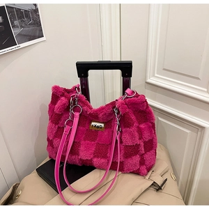Dettaglio della borsa tote in peluche a scacchi con tracolla rosa e catena su valigia
