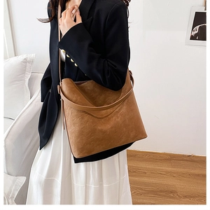 Dettaglio della borsa tote in pelle scamosciata marrone caramello con apertura a mezzaluna