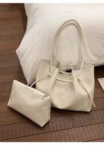 Detail view of cream white faux leather tote bag and matching pouch on wooden floor
