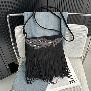 Detail of bohemian black suede crossbody bag with leaf bead embroidery and long fringe trim