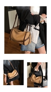 Brown leather Boston bag detail showing cylindrical design and adjustable shoulder straps