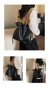 Close-up of black drawstring tote bag with metal chain strap and soft PU texture