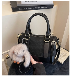 Detailed view of black woven pillow bag with gold zipper and plush rabbit charm
