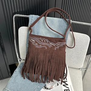 Detail of vintage brown suede crossbody bag with fringe and white bohemian embroidery