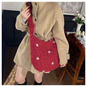 Close-up of red plush tote bag with pink star decorations and soft faux fur texture