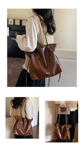 Detail of dark brown leather tote bag with silver chain strap and fashion lettering