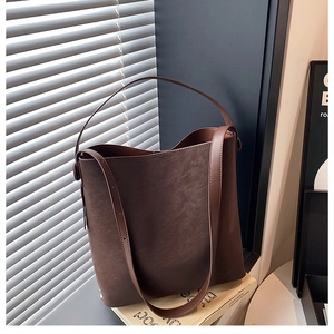 Dettaglio borsa a secchiello caffè scuro con finitura opaca e chiusura magnetica