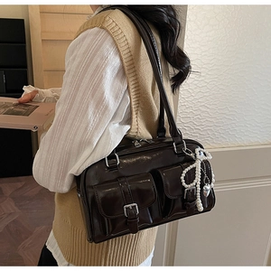 Detail of dark brown leather shoulder bag featuring twin front pockets and silver buckles