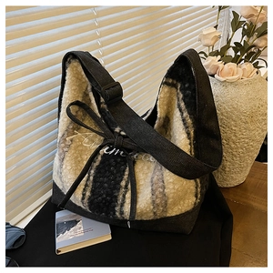 Close-up of striped faux shearling tote bag featuring denim straps and ribbon detail
