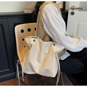 Detail view of the cream leather tote bag featuring a silver chain strap and drawstring