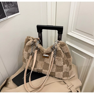 Vista dettagliata della borsa tote scozzese in peluche fissata al manico della valigia