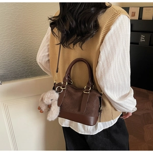 Chic retro brown leather Boston bag styled with a cute plush bunny charm on a model
