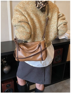 Detail of vintage brown leather duffle bag with gold hardware and contrast trim