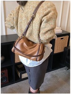 Detail of a brown Boston bag showing textured synthetic leather and gold-toned metal hardware