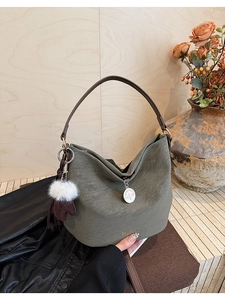Detail of hobo shoulder bag in olive green leather with plush charm and long strap