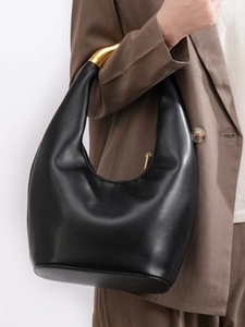 Chic black asymmetric hobo bag with gold metal handle in minimalist urban style