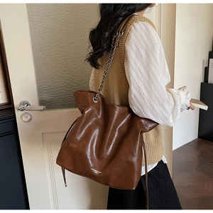 Close-up of brown vintage PU leather tote bag with stylish chain strap and text detail