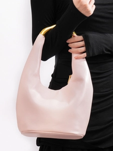 Minimalist light pink hobo bag with unique gold metallic handle shown on a model