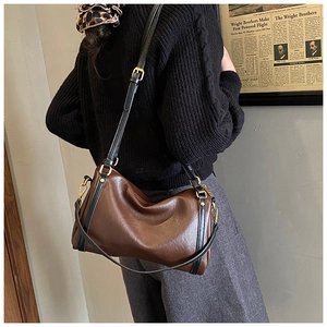 Detailed view of dark brown vintage Boston bag with gold metal hardware and leather texture